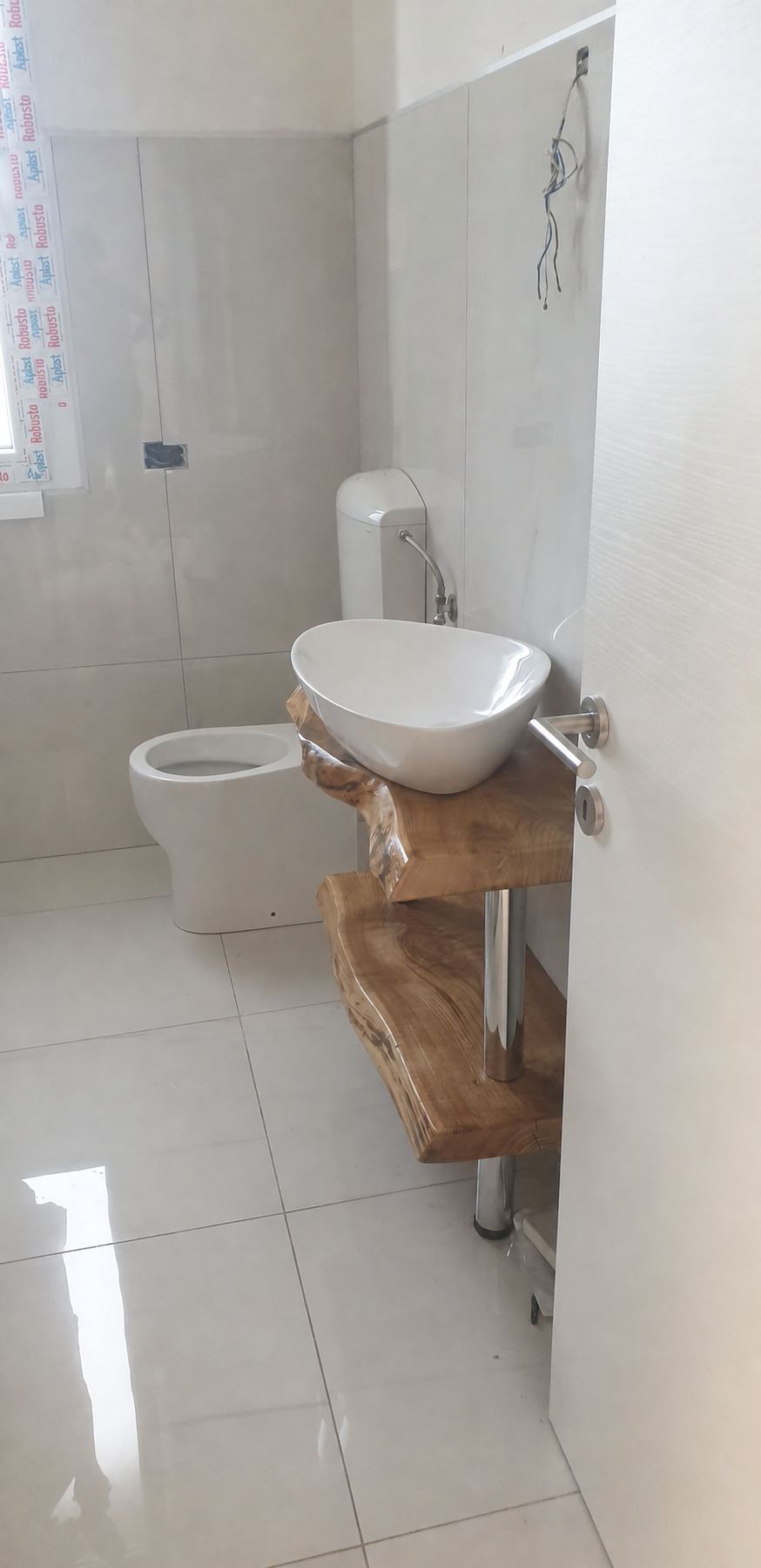 Lavabo appoggiato su travi in legno di ulivo recuperate in un bagno