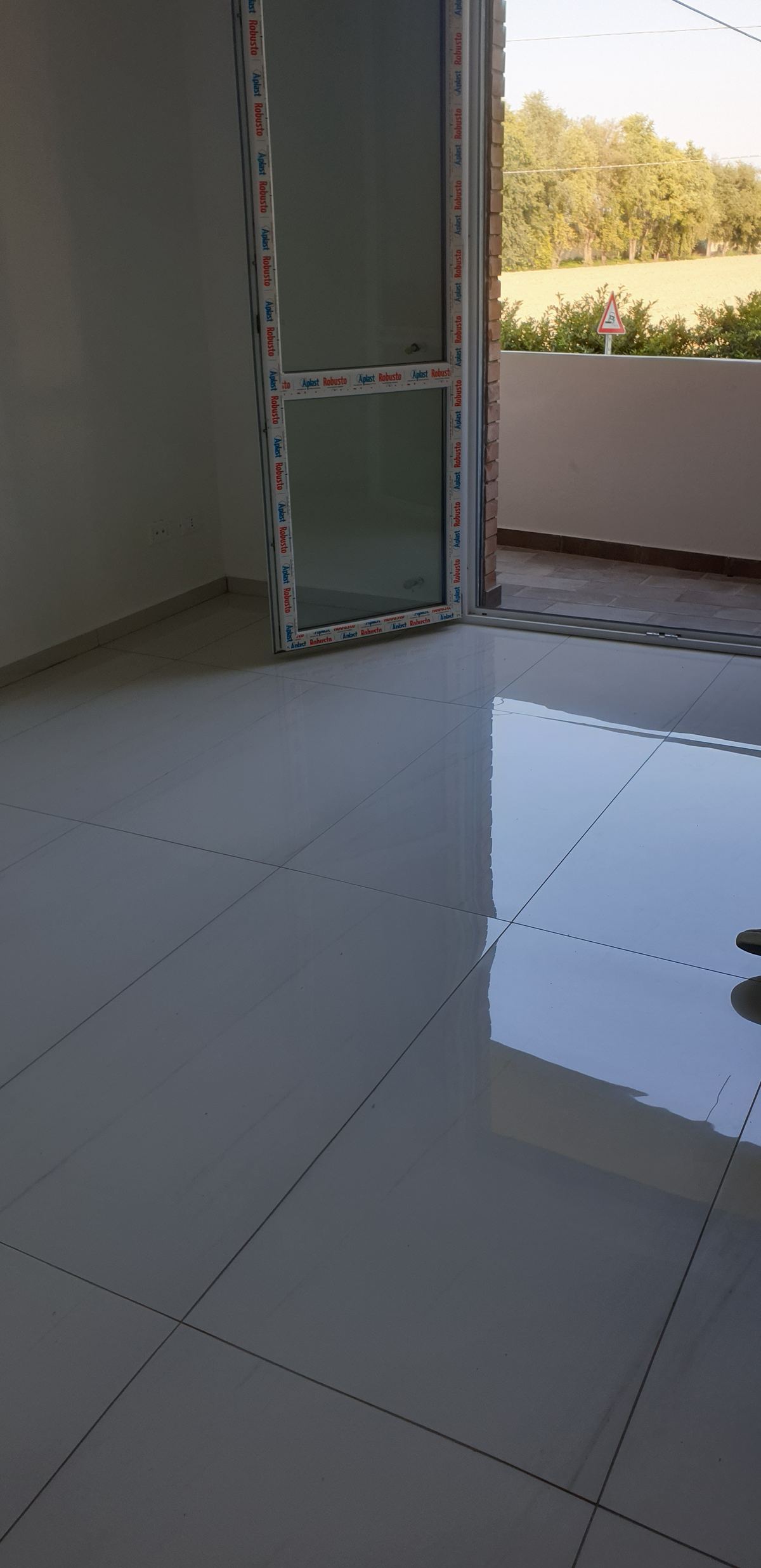 Pavimento interno finito davanti a una portafinestra con un piede visibile sul bordo