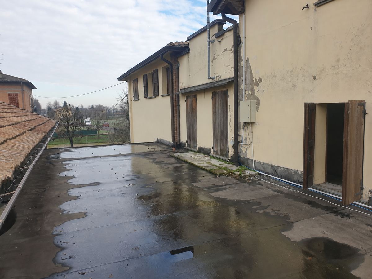 Terrazza esterna con copertura piana, persiane in legno e finestra aperta senza persone