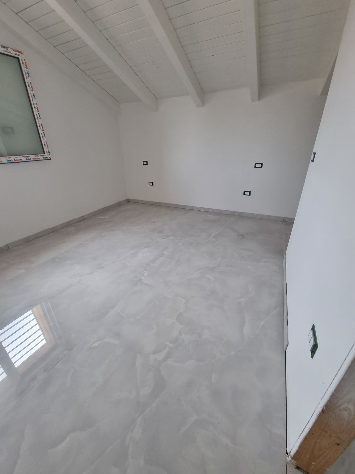 Mansarda completata con travi a vista e pavimento finito