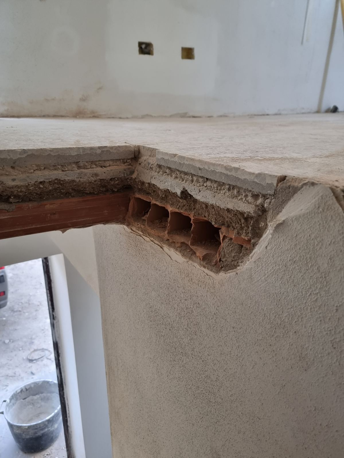 Sezione a vista di un solaio in laterocemento con pignatte in cotto, sormontato da una soglia in pietra